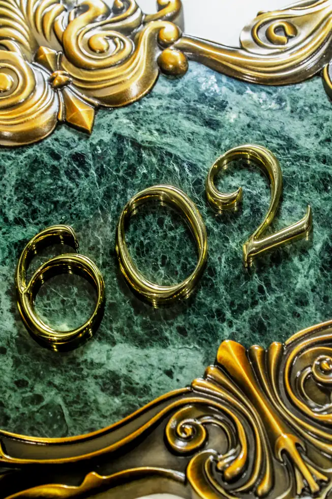 Green relief villa plaque with raised number 602 and antique gold border