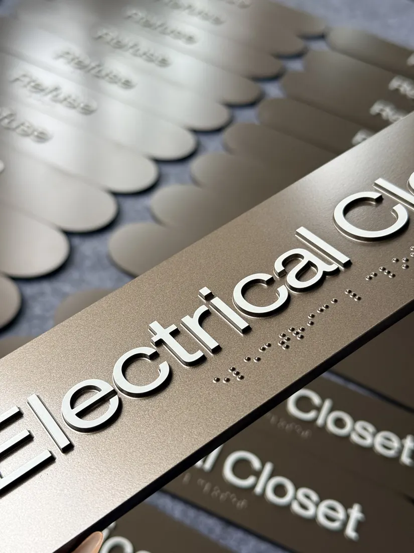 Close-up of tactile raised letters and braille dots on wayfinding signs