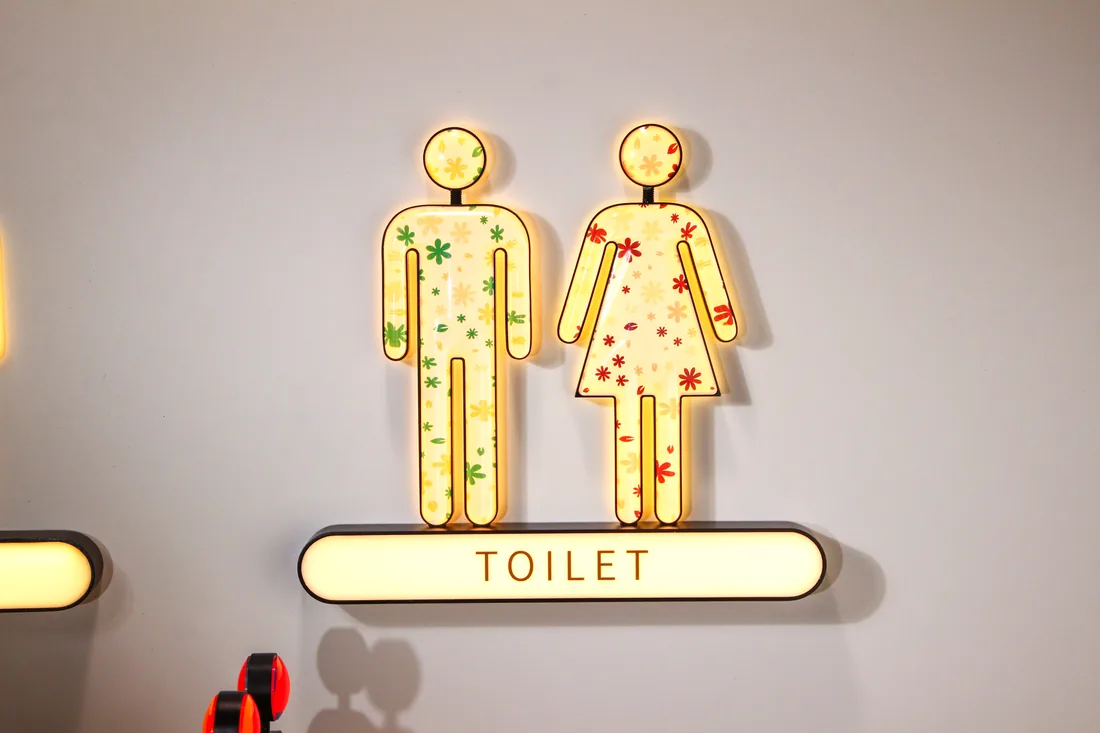 Backlit man and woman pictograms with glowing TOILET sign