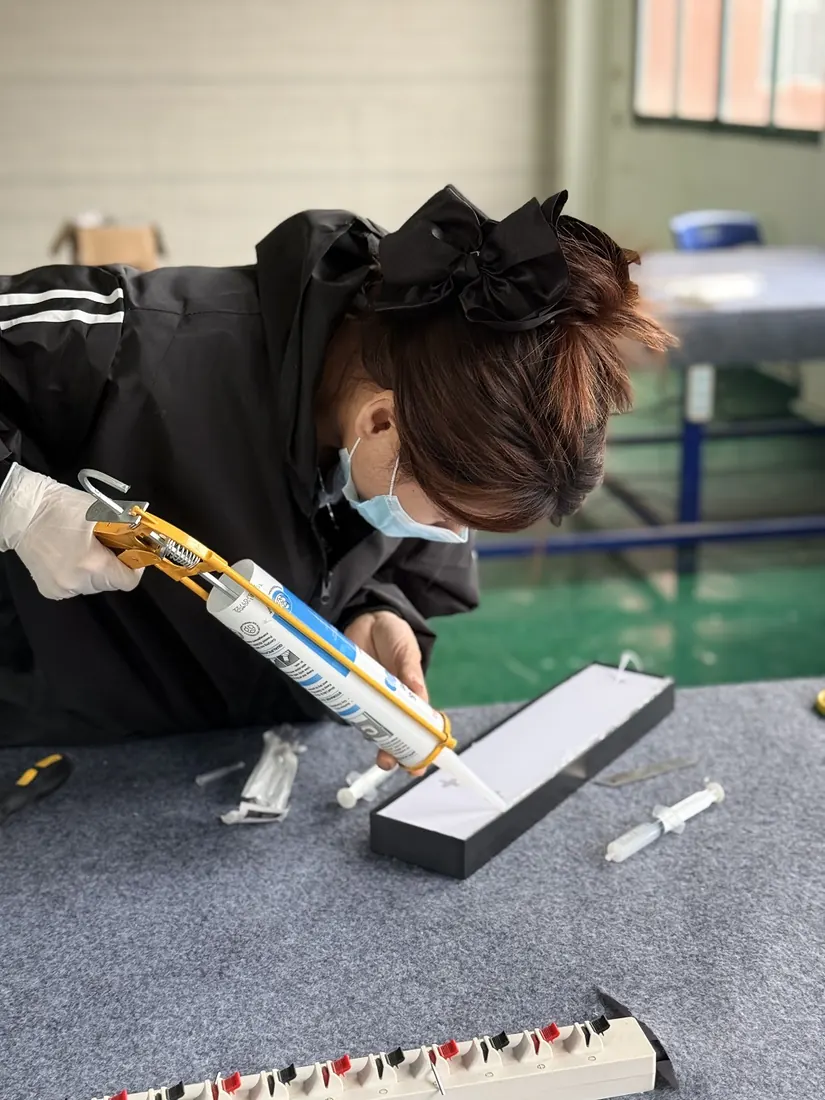 Masked worker bonding an acrylic sign panel on a felt table