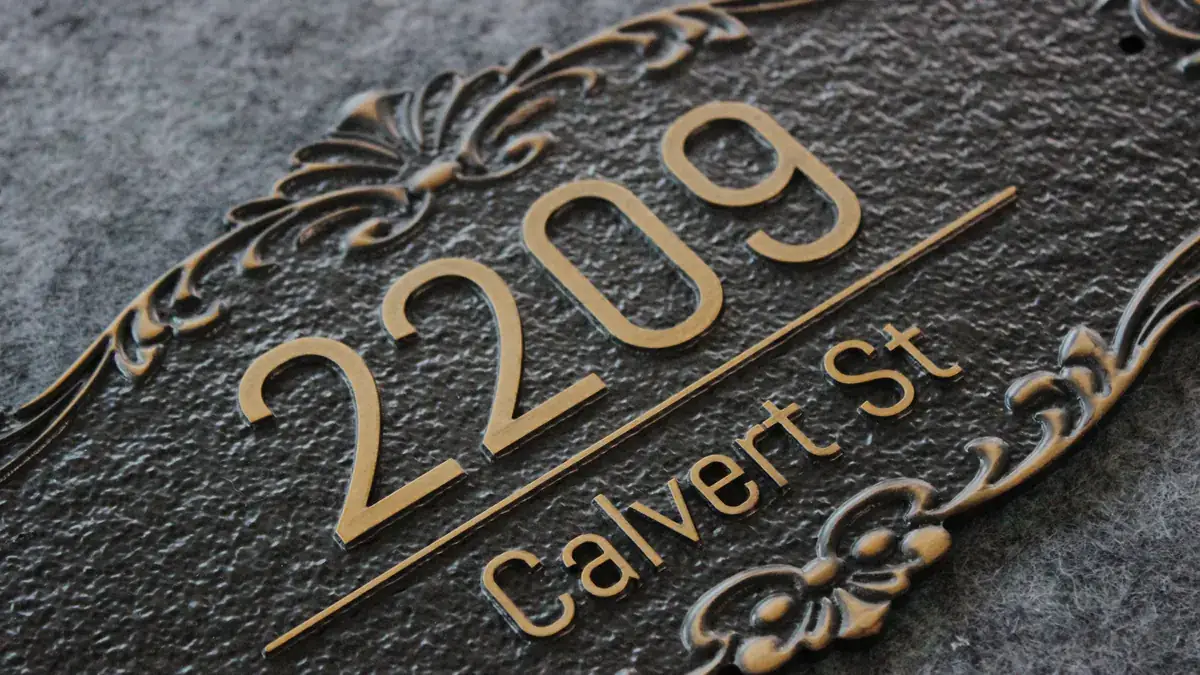 Close-up exterior address plaque with raised brass numbers